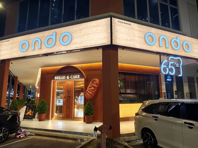 新山 Austin Crest 门市夜间外观：转角店、两侧 ondo 招牌与 65°C 霓虹标记